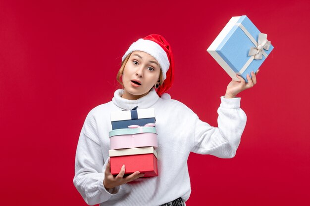 Vue de face jeune femme avec des cadeaux de vacances sur fond rouge