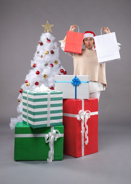 Photo gratuite vue de face jeune femme avec des cadeaux de vacances sur le gris