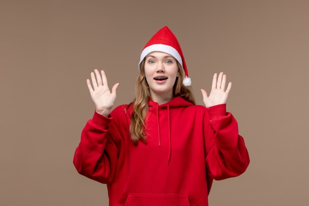 Photo gratuite vue de face jeune femme avec cape de noël sur fond marron émotion vacances de noël