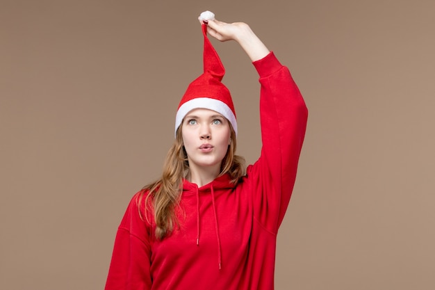 Photo gratuite vue de face jeune femme avec cape rouge sur fond marron vacances d'émotion de noël