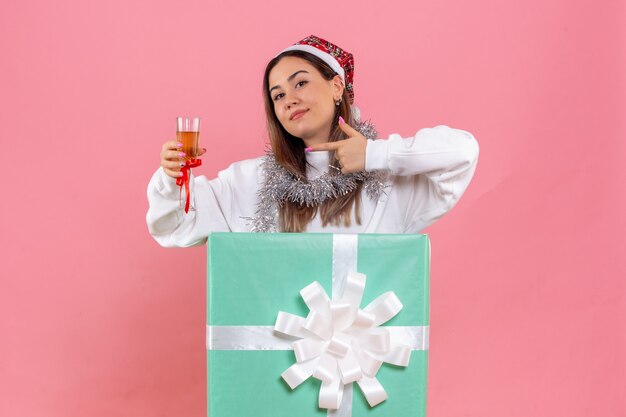 Vue de face de la jeune femme célébrant Noël avec boisson sur mur rose