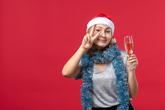 Vue de face jeune femme célébrant le nouvel an à venir sur la couleur du mur rouge vacances de Noël