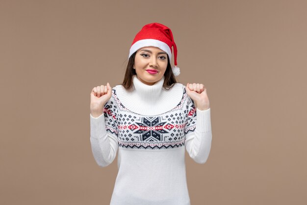 Vue de face jeune femme avec chapeau de Noël rouge sur le bureau marron émotions de Noël nouvel an