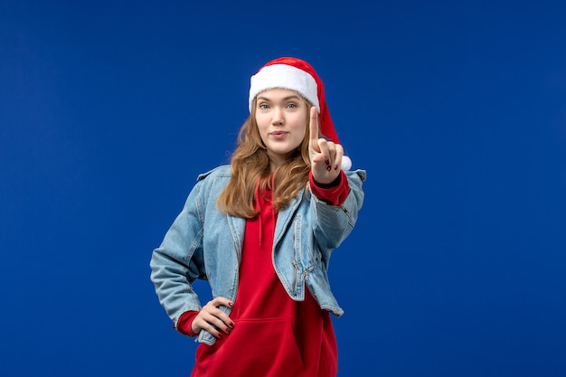 Vue de face jeune femme avec chapeau de Noël rouge sur la couleur de l'émotion de Noël fond bleu