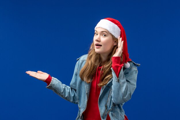 Vue de face jeune femme en chapeau de Noël rouge sur fond bleu couleur d'émotions de Noël