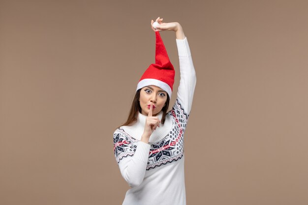 Vue de face jeune femme avec chapeau de Noël rouge sur le fond brun émotion de vacances de Noël