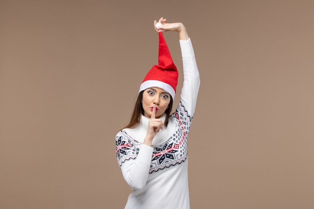 Vue de face jeune femme avec chapeau de Noël rouge sur le fond brun émotion de vacances de Noël