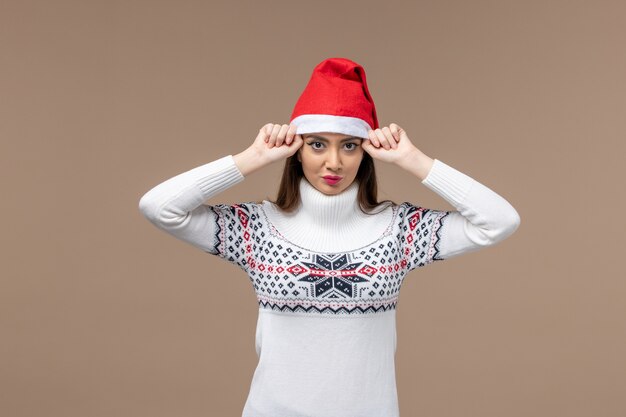 Vue de face jeune femme avec chapeau de Noël rouge sur fond brun foncé émotion de vacances de Noël