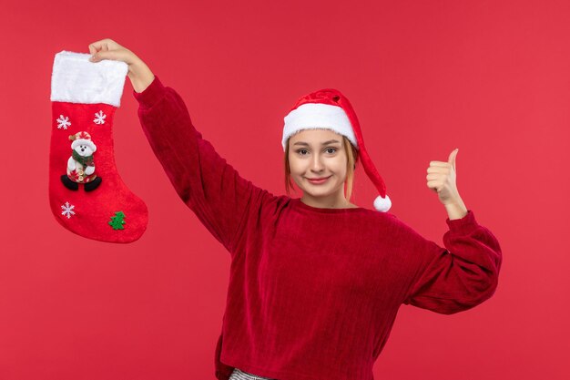 Vue de face jeune femme avec chaussette de noël rouge sur le bureau rouge vacances de noël rouge