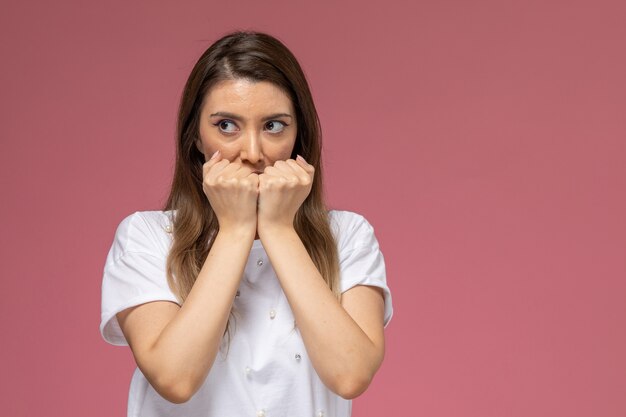 Vue de face jeune femme en chemise blanche couvrant sa bouche avec une expression effrayée