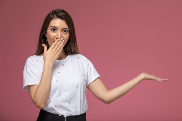 Vue de face jeune femme en chemise blanche couvrant sa bouche sur le mur rose photo couleur modèle femme pose