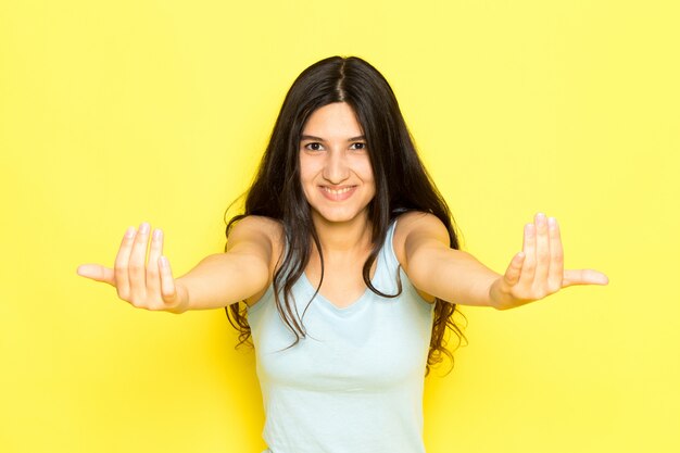 Une vue de face jeune femme en chemise bleue posant et appelant avec le sourire sur son visage