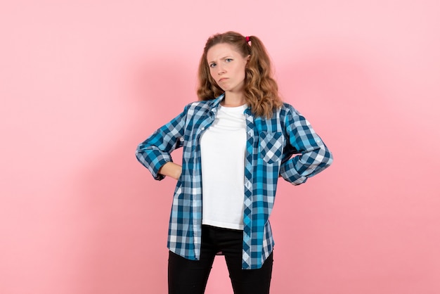 Vue de face jeune femme en chemise à carreaux bleu posant sur le fond rose émotion jeunesse fille kid mode modèle