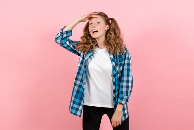 Vue de face jeune femme en chemise à carreaux bleu posant sur fond rose émotions de la jeunesse fille kid mode modèle