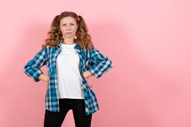 Vue de face jeune femme en chemise à carreaux bleu posant sur le fond rose émotions de la jeunesse fille modèle kid fashion