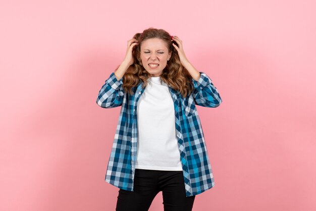 Vue de face jeune femme en chemise à carreaux bleu posant sur fond rose enfant fille jeunesse mode modèle d'émotions