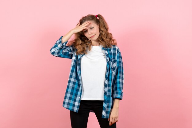 Vue de face jeune femme en chemise à carreaux bleu posant sur le fond rose femme enfant jeunesse modèle couleur émotion