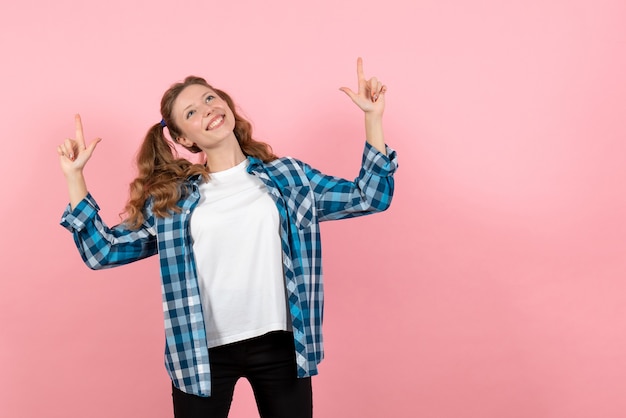 Vue de face jeune femme en chemise à carreaux bleu posant avec sourire sur fond rose femme enfant jeunesse modèle couleur émotion