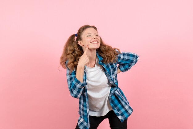 Vue de face jeune femme en chemise à carreaux bleu posant avec le sourire sur le fond rose femme modèle d'émotions mode filles couleur