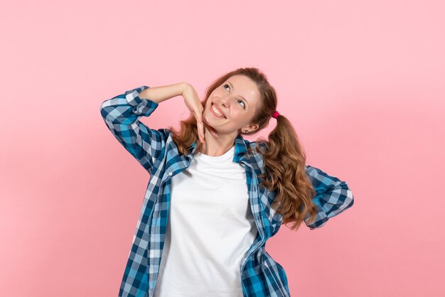 Vue de face jeune femme en chemise à carreaux bleu posant avec le sourire sur le fond rose femme modèle d'émotions mode filles couleur