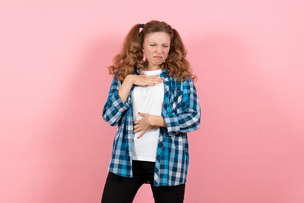 Vue de face jeune femme en chemise à carreaux bleus ayant des troubles respiratoires sur le mur rose émotion des jeunes fille mode modèle enfant