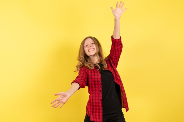 Vue de face jeune femme en chemise à carreaux rouge accueillant quelqu'un sur fond jaune femme modèle d'émotion humaine fashion girl