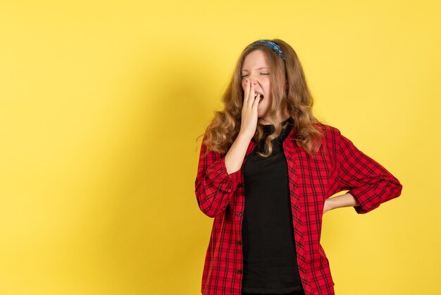 Vue de face jeune femme en chemise à carreaux rouge debout et bâillant sur fond jaune fille couleur femme modèle humain