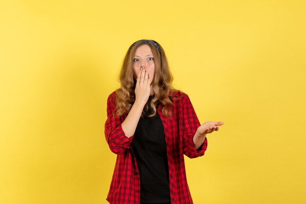 Vue de face jeune femme en chemise à carreaux rouge debout sur fond jaune filles modèle de couleur humaine femme