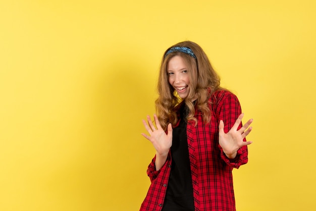 Vue de face jeune femme en chemise à carreaux rouge debout et posant sur fond jaune modèle femme couleur fille humaine