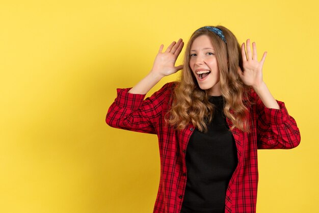 Vue de face jeune femme en chemise à carreaux rouge juste debout et posant sur fond jaune filles modèle de couleur humaine femme