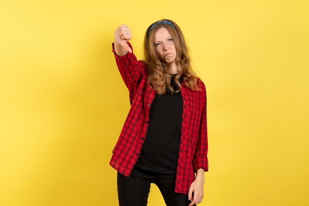 Vue de face jeune femme en chemise à carreaux rouge juste debout et posant sur fond jaune modèle filles femme couleur émotion humaine