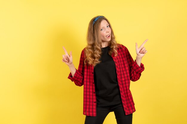 Vue de face jeune femme en chemise à carreaux rouge montrant ses émotions sur fond jaune couleur humaine émotion modèle mode