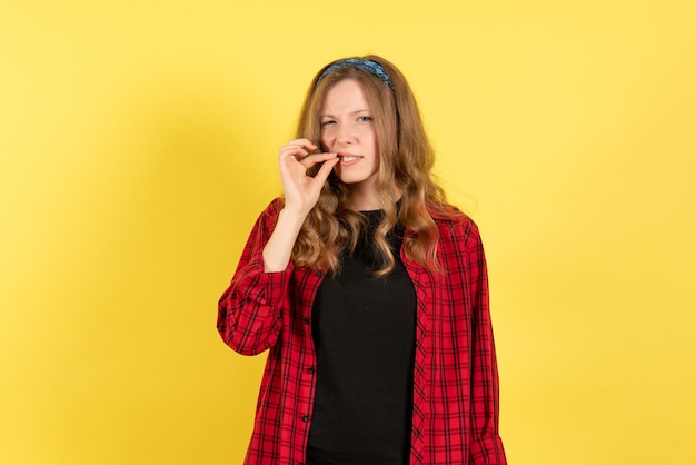 Vue de face jeune femme en chemise à carreaux rouge posant sur fond jaune filles femme émotions couleur modèle humain