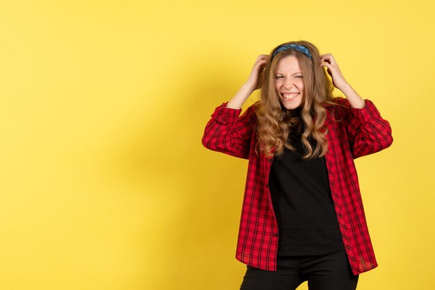 Vue de face jeune femme en chemise à carreaux rouge posant sur fond jaune modèle fille femme couleur émotions femme humaine