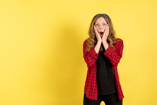 Vue de face jeune femme en chemise à carreaux rouge posant sur fond jaune modèle filles femme émotions couleur féminine humaine