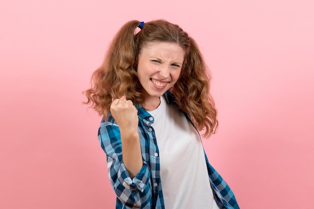 Vue de face jeune femme en chemise à carreaux se réjouissant sur fond rose jeune femme couleur émotions modèle kid