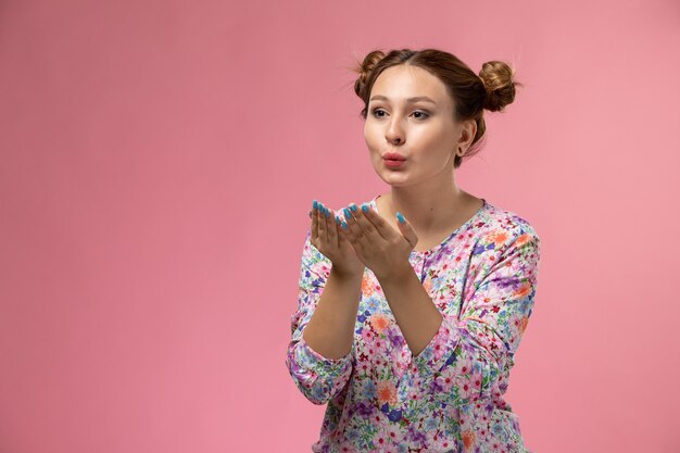 Vue de face jeune femme en chemise conçue de fleurs et un jean bleu envoyant des bisous sur le fond rose