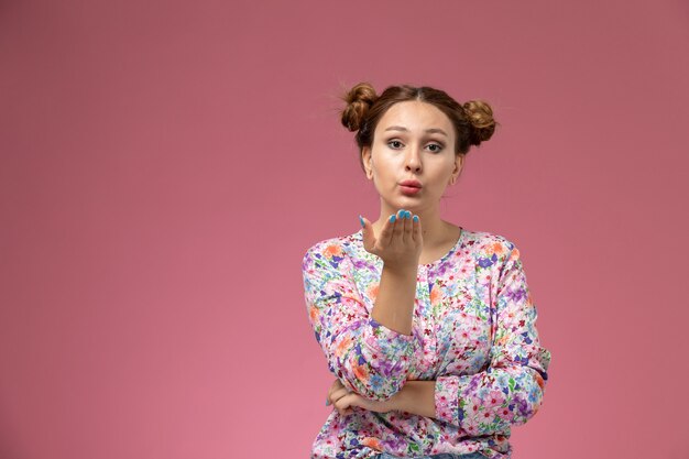 Vue de face jeune femme en chemise conçue de fleurs et un jean bleu envoyant des bisous sur le fond rose