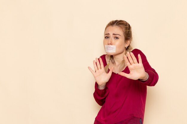 Vue de face jeune femme en chemise rouge avec la bouche attachée sur le tissu féminin de l'espace léger