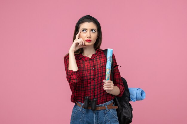 Vue de face jeune femme en chemise rouge avec carte sur fond rose couleurs mode femme