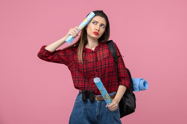 Vue de face jeune femme en chemise rouge avec des cartes sur le fond rose couleur femme humaine