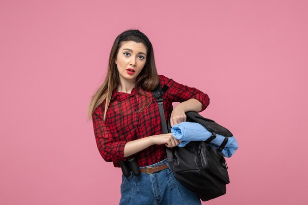 Vue de face jeune femme en chemise rouge avec sac sur le modèle photo femme fond rose