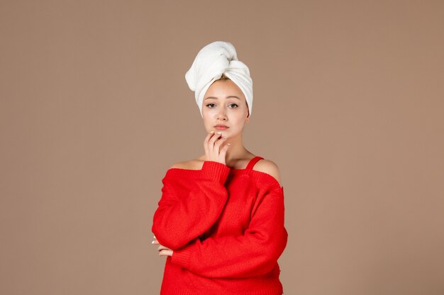 vue de face d'une jeune femme en chemise rouge avec une serviette sur sa tête mur marron