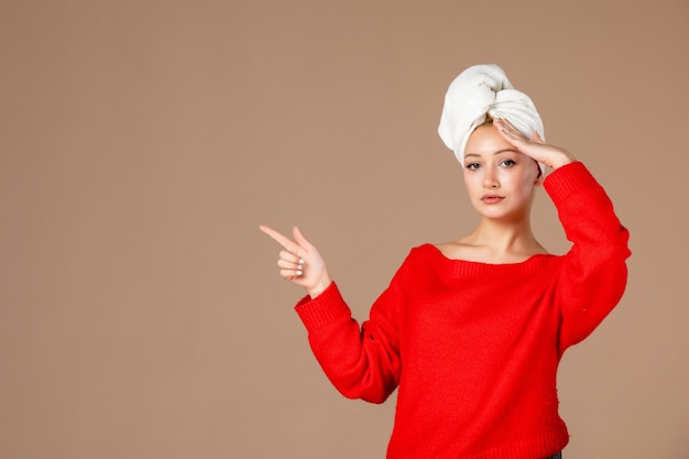 vue de face jeune femme en chemise rouge avec une serviette sur la tête sur un mur marron