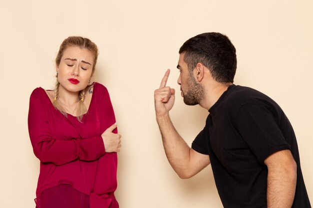 Vue de face jeune femme en chemise rouge souffre de menaces physiques et de violence sur le tissu féminin de l'espace crème