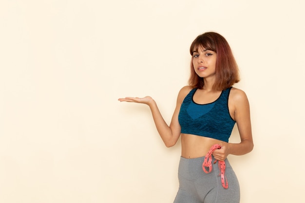 Vue de face de la jeune femme avec un corps en forme de chemise bleue sur un mur blanc clair