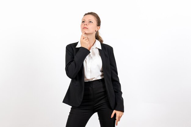 Vue de face jeune femme en costume classique strict posant et pensant sur fond blanc travail entreprise travail femme costume femme