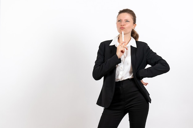 Vue de face jeune femme en costume classique strict tenant un stylo sur un bureau blanc femme costume de travail entreprise travail féminin