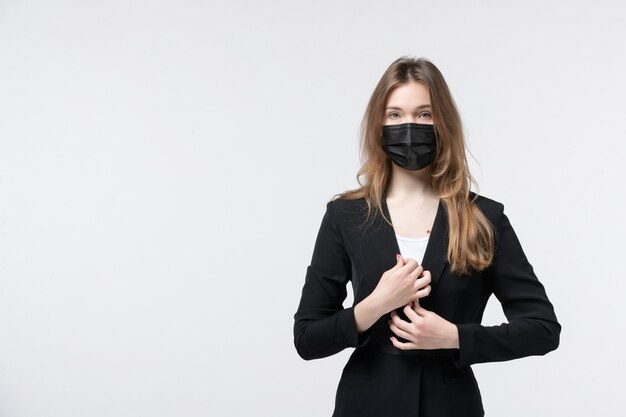 Vue de face d'une jeune femme en costume portant un masque chirurgical et posant pour la caméra sur blanc