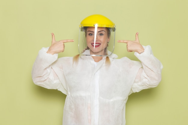 Vue de face jeune femme en costume spécial blanc et casque jaune souriant sur l'emploi de l'espace vert